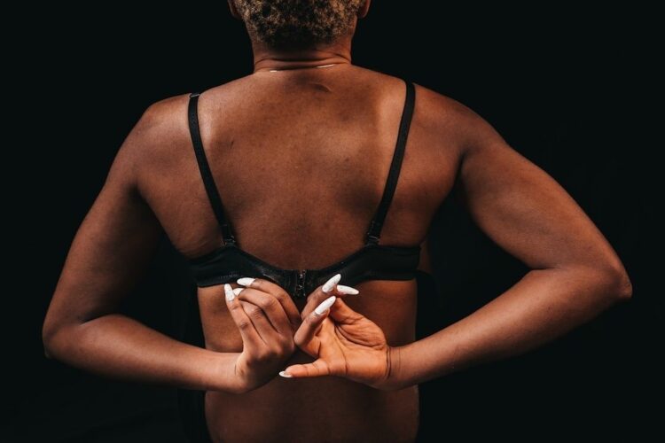 Person bakifrån som justerar spännet på en svart sport-bh